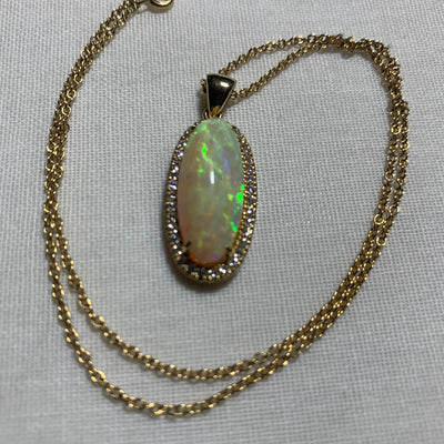 An18-carat gold, opal, and diamond pendant on a chain with a pair of earrings